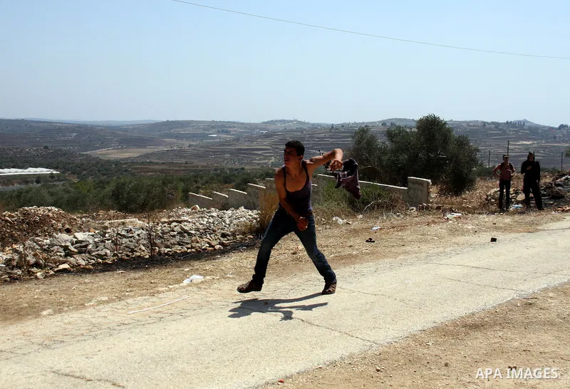 A Palestinian protestor hurls stones toward Israeli soldiers during a demonstration against the closure of a road during the second Intifada by Jewish settlers from the nearby settlement of Kadumim , on July 22, 2011 in...