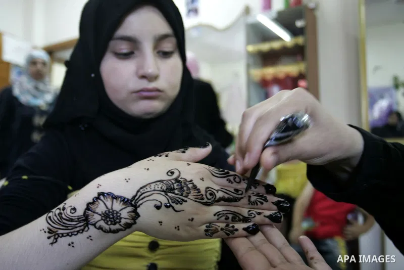 A Palestinian woman applies henna on the hand of a girl during a summer camp organised by the Ministry of Youth and Sports in Rafah, southern Gaza Strip, on July 23, 2011. Photo by Abed Rahim Khatib