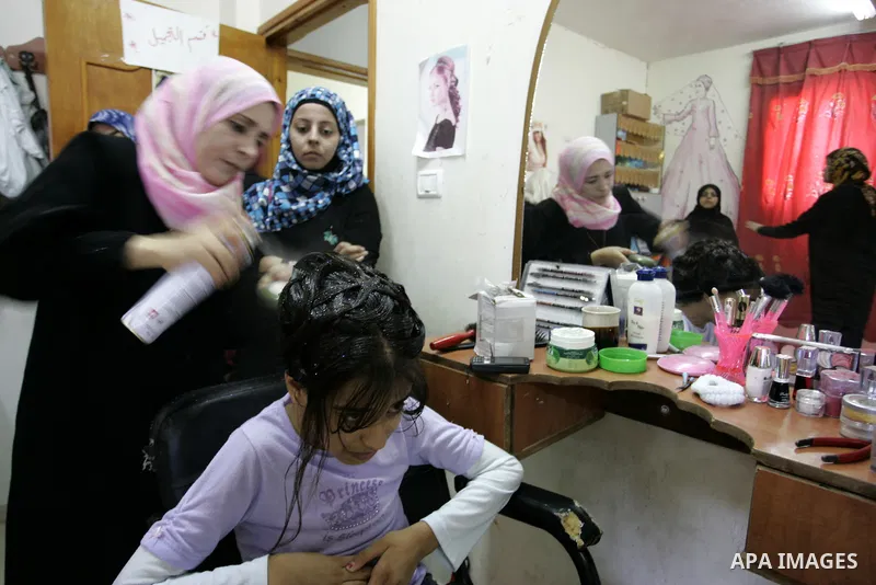 A Palestinian woman applies makeup on the face of a girl during a summer camp organised by the Ministry of Youth and Sports in Rafah, southern Gaza Strip, on July 23, 2011. Photo by Abed Rahim Khatib