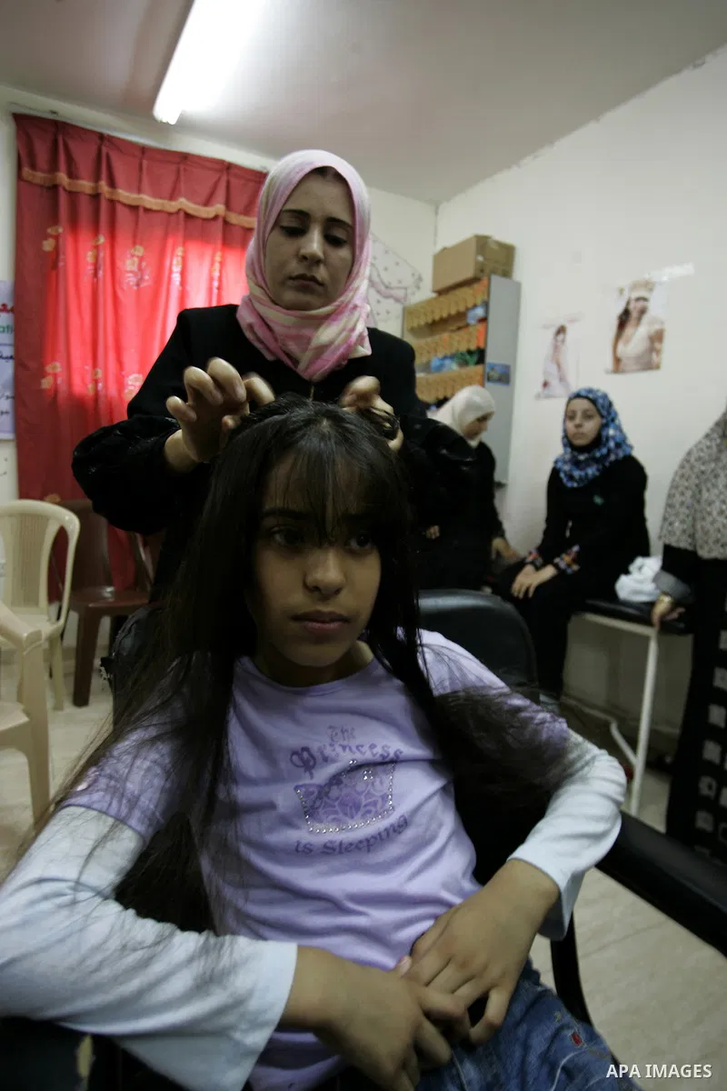 A Palestinian woman applies makeup on the face of a girl during a summer camp organised by the Ministry of Youth and Sports in Rafah, southern Gaza Strip, on July 23, 2011. Photo by Abed Rahim Khatib