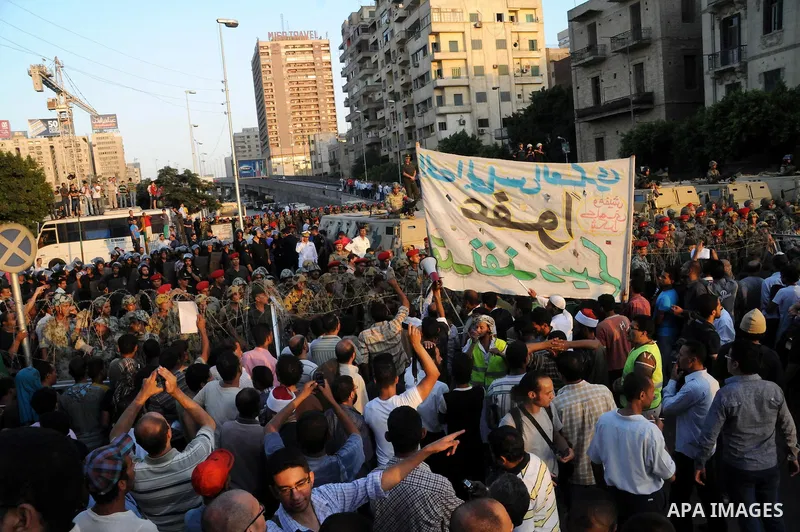 Egyptian soldiers stand guard behind barbed wire as protesters demonstrate outside the defence ministry, the headquarters of the Supreme Council of the Armed Forces, in Cairo on July 23, 2011 to show their anger at the r...
