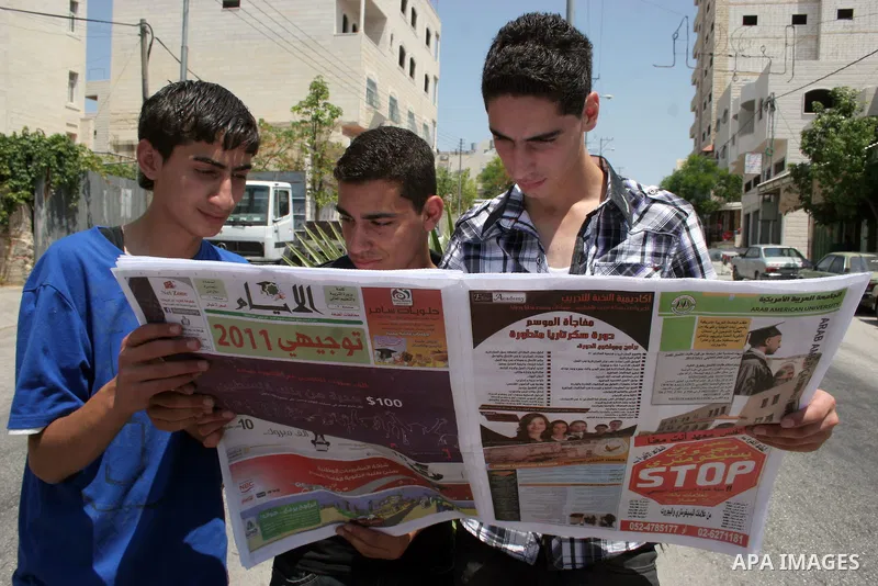 Palestinians bring newspapers and watching the results of high school exams "tawjihi", in the West Bank city of Hebron on July 24, 2011.Photo by Najeh Hashlamoun