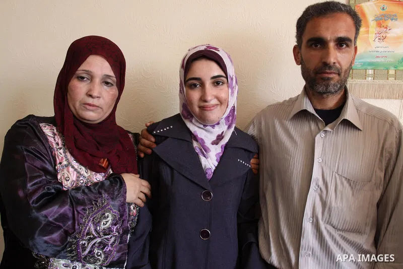 A Palestinian secondary school student and the first in section literary, Asmaa` Al-Sahhar, cries with joy and celebrating with her family after hear her result in Gaza city on July 24,2011. The Ministry of Education in...