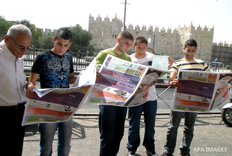 Palestinian students read a local newspaper as they look for their results of final high school exams, known as "Tawjihi" in Jerusalem's old city on July 24,2011.. Photo by Mahfouz Abu Turk