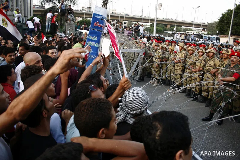 Egyptian soldiers stand guard behind barbed wire as protesters demonstrate outside the defence ministry, the headquarters of the Supreme Council of the Armed Forces, in Cairo on July 23, 2011 to show their anger at the r...