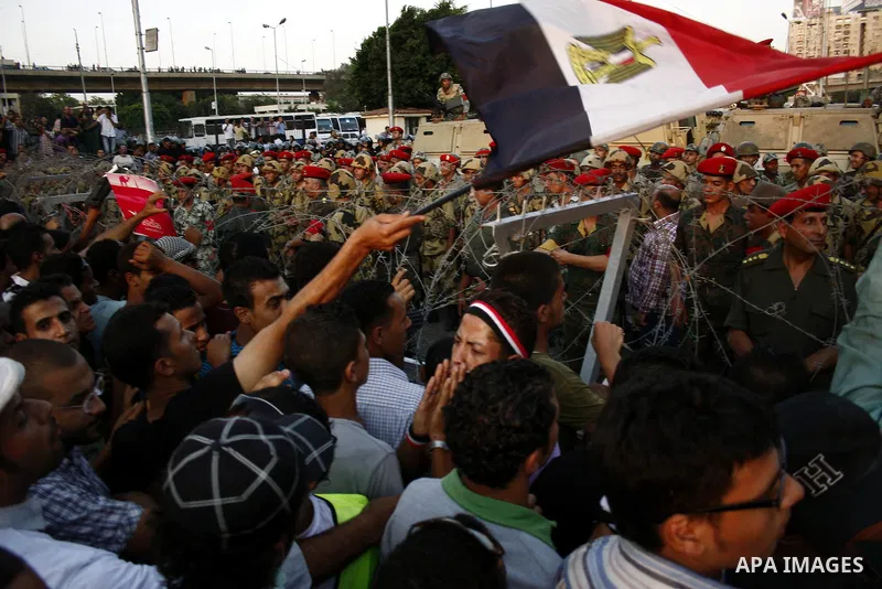 Egyptian soldiers stand guard behind barbed wire as protesters demonstrate outside the defence ministry, the headquarters of the Supreme Council of the Armed Forces, in Cairo on July 23, 2011 to show their anger at the r...