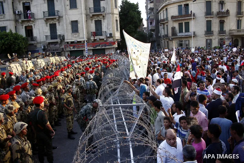 Egyptian soldiers stand guard behind barbed wire as protesters demonstrate outside the defence ministry, the headquarters of the Supreme Council of the Armed Forces, in Cairo on July 23, 2011 to show their anger at the r...