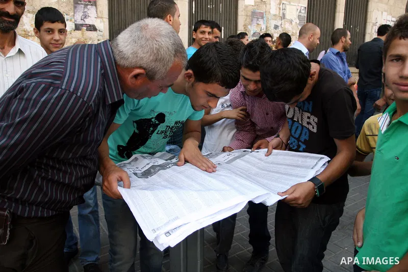 Palestinian students read a local newspaper as they look for their results of final high school exams, known as "Tawjihi" in the West Bank city of Ramallah on July 24,2011. Photo by Issam Rimawi