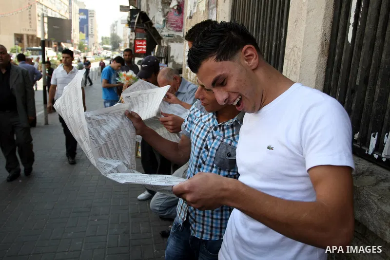 Palestinian students read a local newspaper as they look for their results of final high school exams, known as "Tawjihi" in the West Bank city of Ramallah on July 24,2011. Photo by Issam Rimawi