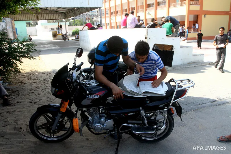 Palestinian secondary school students read a local newspaper to find their results in Gaza city on July 24,2011. The Ministry of Education in Gaza Strip and the West Bank announced the results together. Photo by Ashraf a...