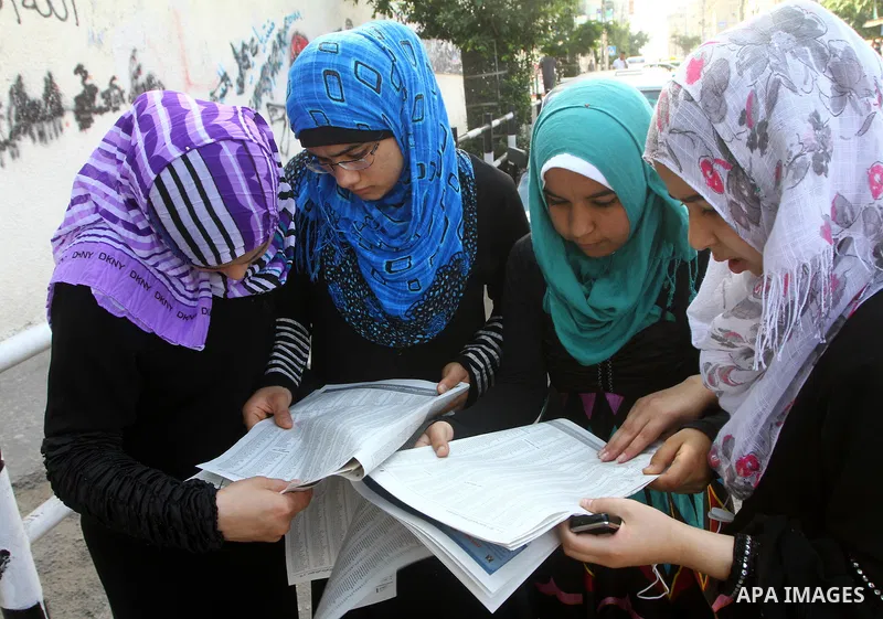 Palestinian secondary school students read a local newspaper to find their results in Gaza city on July 24,2011. The Ministry of Education in Gaza Strip and the West Bank announced the results together. Photo by Ashraf a...