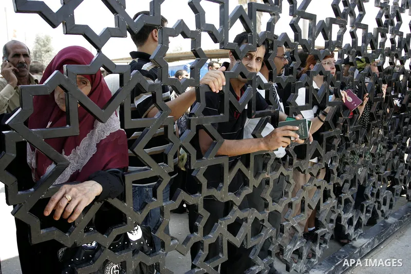 Palestinians stand behind the iron gate of the Rafah border waiting to cross the Rafah border crossing with Egypt, in the southern Gaza Strip on July 25, 2011. Photo by Abed Rahim Khatib