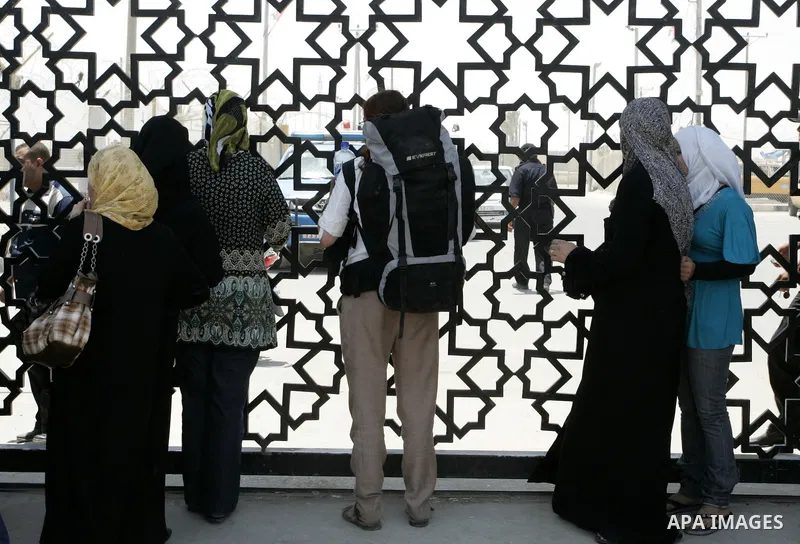 Palestinians stand behind the iron gate of the Rafah border waiting to cross the Rafah border crossing with Egypt, in the southern Gaza Strip on July 25, 2011. Photo by Abed Rahim Khatib