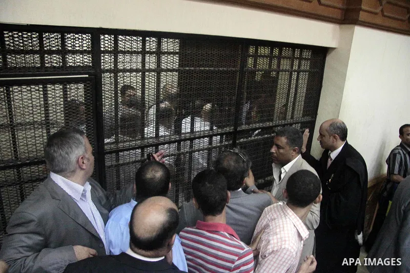 Journalists and bodyguards stand in the Cairo court room as defendants are kept behind bars, including Egypt's former Interior Minister Habib el-Adly, seen behind bars 3rd left, during their trial on charges relating to...