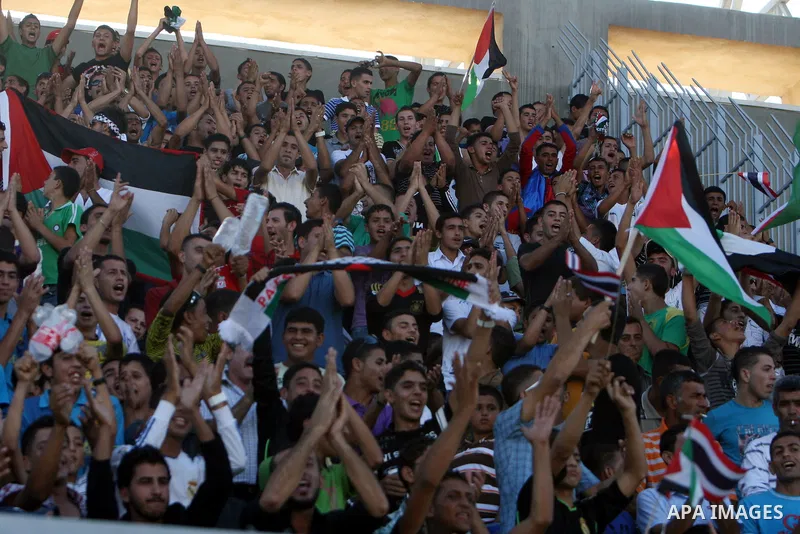 Fans wave Palestinian flags as they cheer during the 2014 FIFA World Cup qualification soccer match between Thailand and the Palestinian Territories at A-Ram stadium near Jerusalem July 28, 2011 Photo by Issam Rimawi