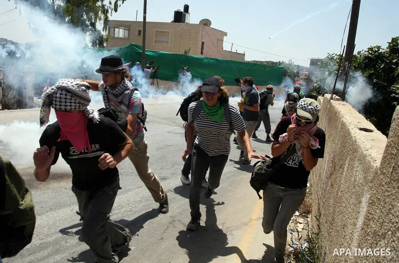 Pro-Palestinian protesters run away from tear gas fired by Israeli security force officers during clashes at a weekly protest in the West Bank village of Nabi Saleh, near Ramallah July 29, 2011. Photo by Issam Rimawi