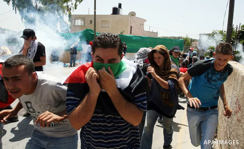 Pro-Palestinian protesters run away from tear gas fired by Israeli security force officers during clashes at a weekly protest in the West Bank village of Nabi Saleh, near Ramallah July 29, 2011. Photo by Issam Rimawi