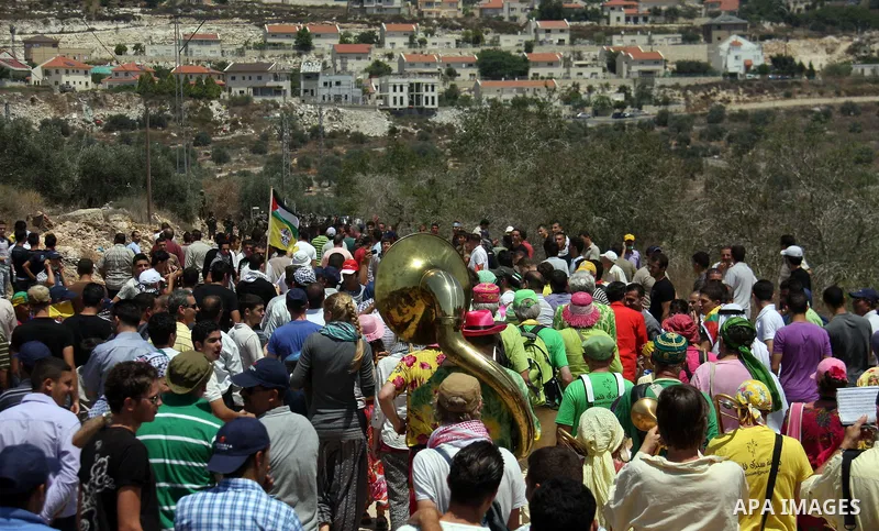 Holland artists from the Dutch street band sing ,during a protest about Palestinian access to lands in the area, in the village of Kufr Qaddum near the Israeli settlement of Kdumim, in the northern West Bank Friday, July...