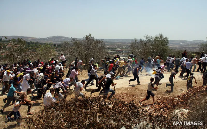 Palestinians run away from tear gas fired by Israeli soldiers, during a protest about Palestinian access to lands in the area, in the village of Kufr Qaddum near the Israeli settlement of Kdumim, in the northern West Ban...