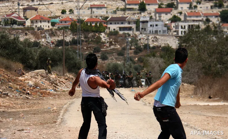 Palestinian youths hurl stones at Israeli security forces, during a protest about Palestinian access to lands in the area, in the village of Kufr Qaddum near the Israeli settlement of Kdumim, in the northern West Bank Fr...