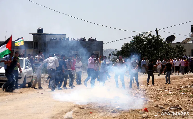 Palestinians run away from tear gas fired by Israeli soldiers, during a protest about Palestinian access to lands in the area, in the village of Kufr Qaddum near the Israeli settlement of Kdumim, in the northern West Ban...