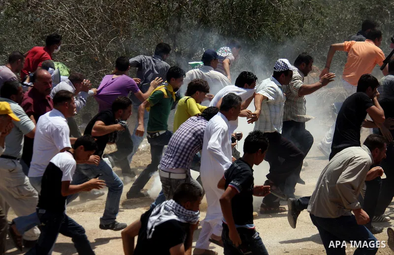 Palestinians run away from tear gas fired by Israeli soldiers, during a protest about Palestinian access to lands in the area, in the village of Kufr Qaddum near the Israeli settlement of Kdumim, in the northern West Ban...