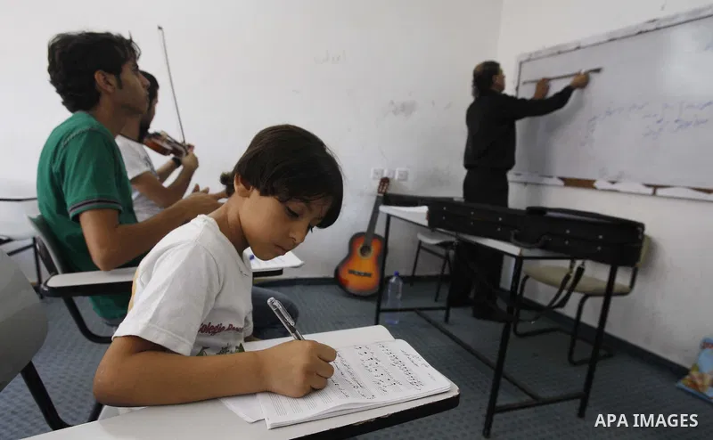 A Palestinian Music teacher during teaching students the lessons on musical instruments at the Gaza College in the Department of Music in Gaza city on July 30, 2011. Photo by Mahmud Nassar