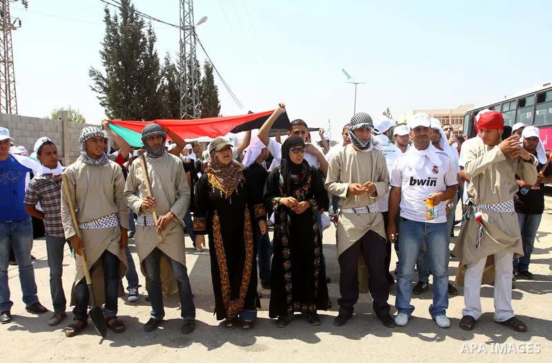 Palestinian protesters wave national flags during a demonstration on July 30, 2011 on the outskirts of Gaza City against the military zone Israel created on Palestinian land, east of the city, as a buffer between its bor...