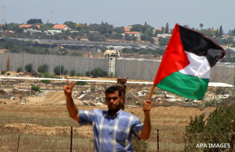 Palestinian protesters wave national flags during a demonstration on July 30, 2011 on the outskirts of Gaza City against the military zone Israel created on Palestinian land, east of the city, as a buffer between its bor...