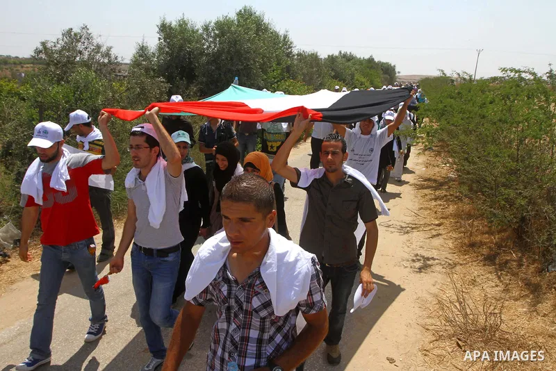 Palestinian protesters wave national flags during a demonstration on July 30, 2011 on the outskirts of Gaza City against the military zone Israel created on Palestinian land, east of the city, as a buffer between its bor...