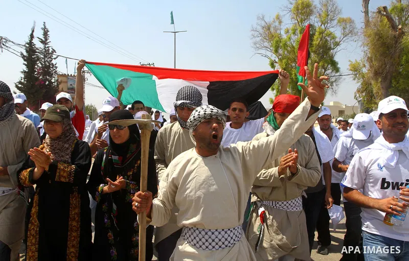 Palestinian protesters wave national flags during a demonstration on July 30, 2011 on the outskirts of Gaza City against the military zone Israel created on Palestinian land, east of the city, as a buffer between its bor...