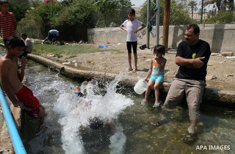 Palestinians immerse themselves in a running stream of channelled irrigation water as they cool off in the biblical city of Jericho where the temperatures soared to 47 degrees Celsius, on July 30, 2011. Photo by Issam Ri...