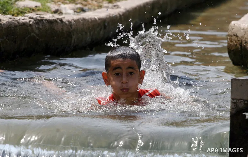 Palestinians immerse themselves in a running stream of channelled irrigation water as they cool off in the biblical city of Jericho where the temperatures soared to 47 degrees Celsius, on July 30, 2011. Photo by Issam Ri...