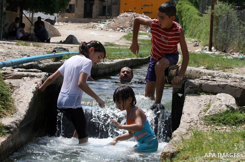 Palestinians immerse themselves in a running stream of channelled irrigation water as they cool off in the biblical city of Jericho where the temperatures soared to 47 degrees Celsius, on July 30, 2011. Photo by Issam Ri...