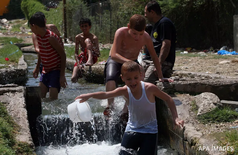 Palestinians immerse themselves in a running stream of channelled irrigation water as they cool off in the biblical city of Jericho where the temperatures soared to 47 degrees Celsius, on July 30, 2011. Photo by Issam Ri...