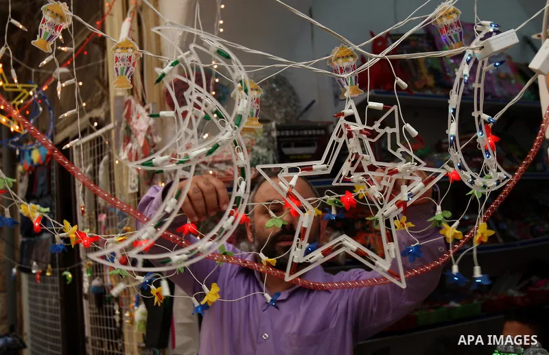 Palestinian vendor stand next to a shop, decorated with Ramadan festive lights, in the West Bank city of Nablus, Sunday, July 31, 2011. Muslims throughout the world will celebrate the holy fasting month of Ramadan, the h...