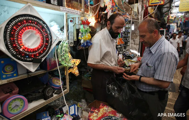 Palestinian vendor stand next to a shop, decorated with Ramadan festive lights, in the West Bank city of Nablus, Sunday, July 31, 2011. Muslims throughout the world will celebrate the holy fasting month of Ramadan, the h...
