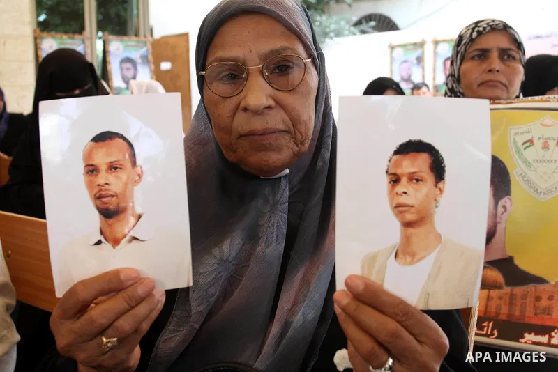 A Palestinians woman holds pictures of their prisoned relatives in Israeli jails as they gather in a weekly activity calling for their liberty at the Red Cross headquarters in Gaza City on Aug.1, 2011. About 7000 prisone...