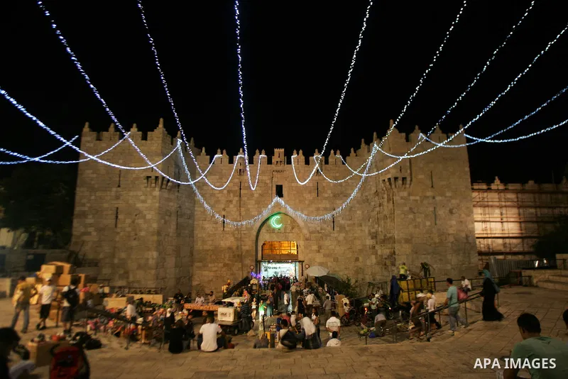 Palestinians stand under decorations for the upcoming holy month of Ramadan near Damascus Gate in Jerusalem's Old City July 31, 2011. Muslims around the world abstain from eating, drinking and conducting sexual relations...