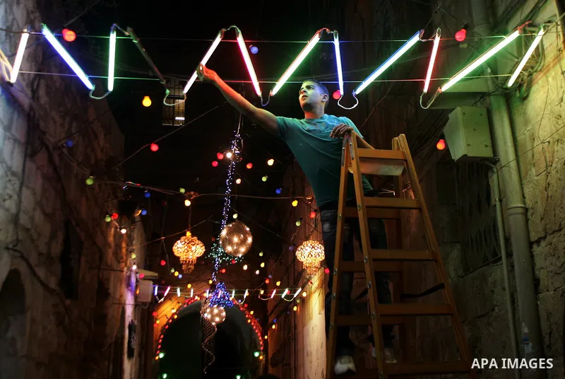 A Palestinian man hangs decorations for the upcoming holy month of Ramadan outside his home in Jerusalem's Old City July 31, 2011. Muslims around the world abstain from eating, drinking and conducting sexual relations fr...