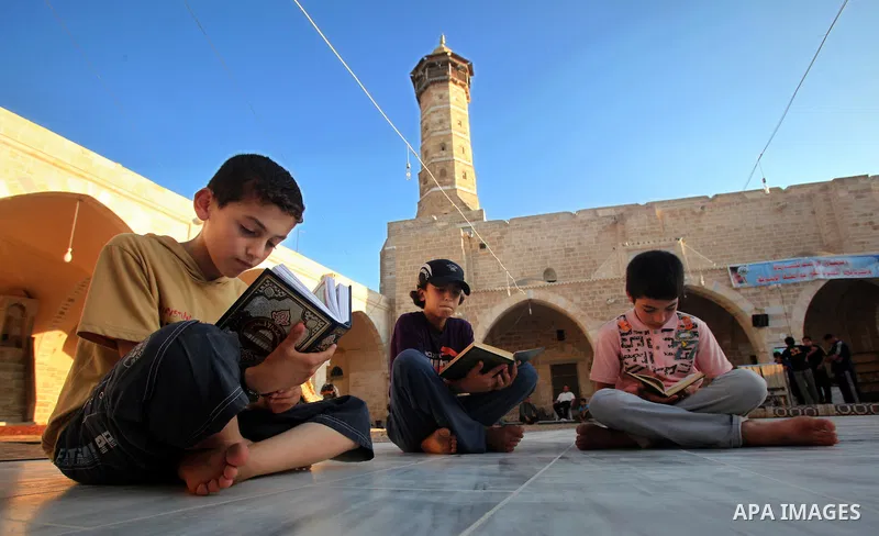 Palestinian boys read the Koran at the al-Omari mosque in Gaza City on the first day of the Muslim holy fasting month of Ramadan on 01 August 2011. Muslims throughout the world are celebrating the holy fasting month of R...
