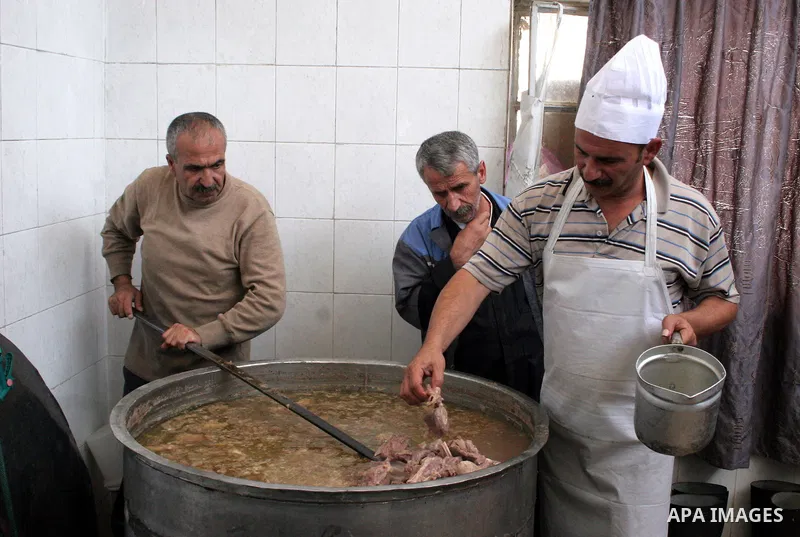 Palestinian families carry containers as they wait to receive free food for 'Iftar', the meal that breaks the daily fast during Ramadan, at an Islamic Council charity in the centre of the West Bank city of Hebron on Augu...
