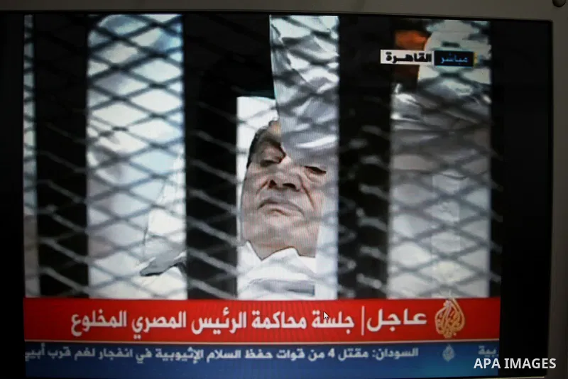 This video image taken from Egyptian State Television shows 83-year-old Hosni Mubarak laying on a hospital bed inside a cage of mesh and iron bars in a Cairo courtroom Wednesday Aug. 3, 2011 as his historic trial began o...