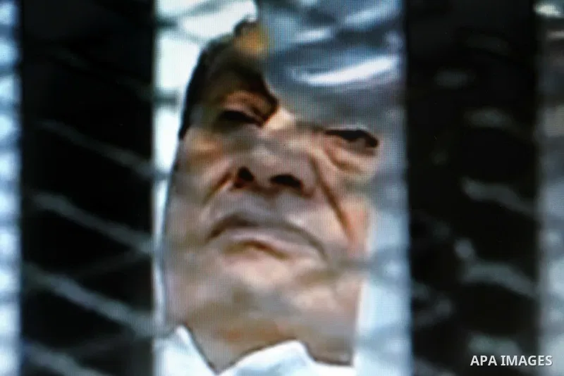 This video image taken from Egyptian State Television shows 83-year-old Hosni Mubarak laying on a hospital bed inside a cage of mesh and iron bars in a Cairo courtroom Wednesday Aug. 3, 2011 as his historic trial began o...