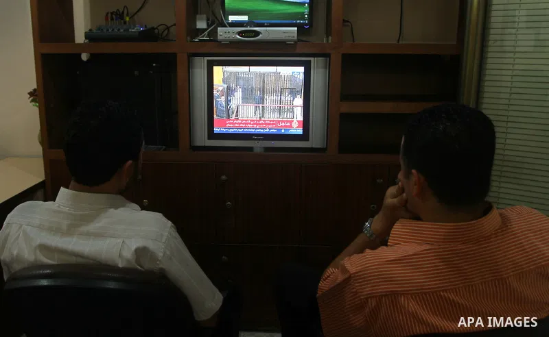 Palestinians watch the video image taken from Egyptian State Television shows 83-year-old Hosni Mubarak laying on a hospital bed inside a cage of mesh and iron bars as he flanked by his sons Alaa, left, and Gamal right,...