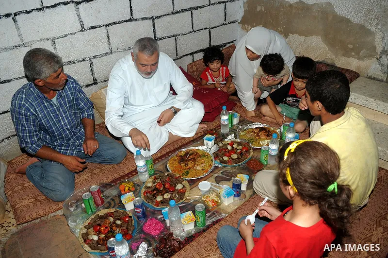 Palestinian Prime Minister in Gaza Strip, Ismail Haniya during eating the meal of "Iftar" with a poor family in the holy fasting month of Ramadan at al-Shati refugee camp beach, western Gaza city on Aug. 3, 2011. Photo b...