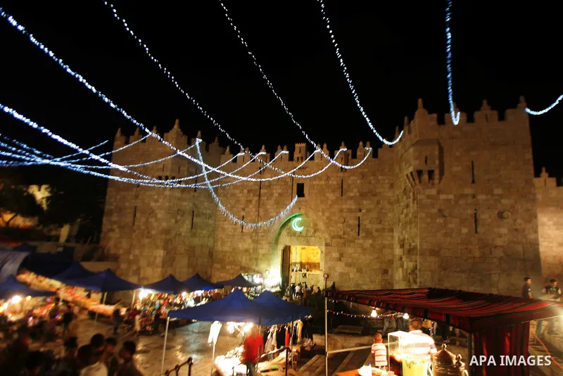 Palestinians stand under decorations in the nights of the holy month of Ramadan near Damascus Gate in Jerusalem's Old City on Aug. 3, 2011. Muslims around the world abstain from eating, drinking and conducting sexual rel...