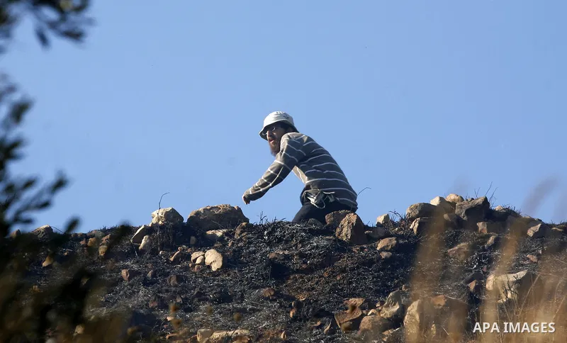 Israeli settlers hurl rocks at Palestinians, not seen, on the outskirts of Burin village, near the Jewish settlement burning fields on Palestinian land close to the village of Burin, near the West Bank town of Nablus, on...