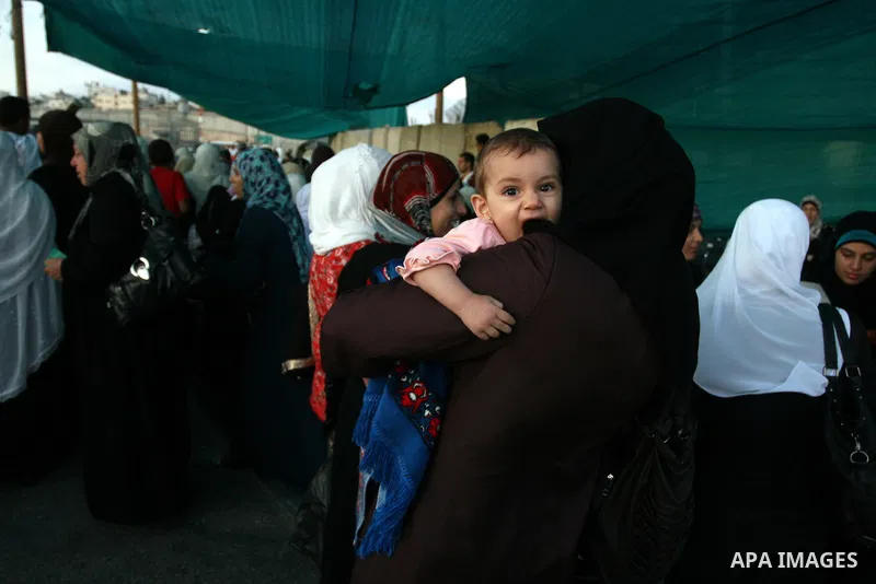 Palestinian women wait to cross the Qalandia checkpoint on their way to pray at the Al Aqsa Mosque on the first Friday of the Muslim holy month of Ramadan, at the Qalandia checkpoint between the West Bank city of Ramalla...