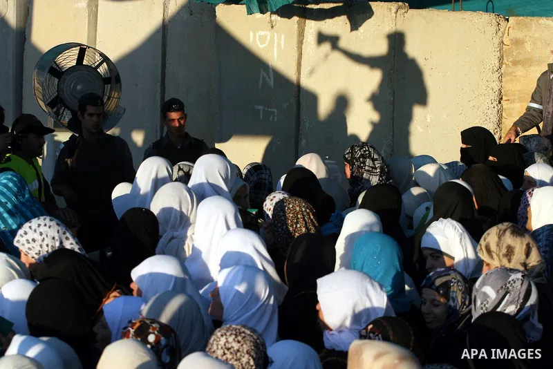 Palestinian women wait to cross the Qalandia checkpoint on their way to pray at the Al Aqsa Mosque on the first Friday of the Muslim holy month of Ramadan, at the Qalandia checkpoint between the West Bank city of Ramalla...